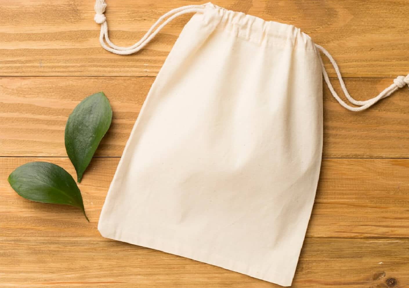 Close up of a small tan draw string pouch on a wooden surface.